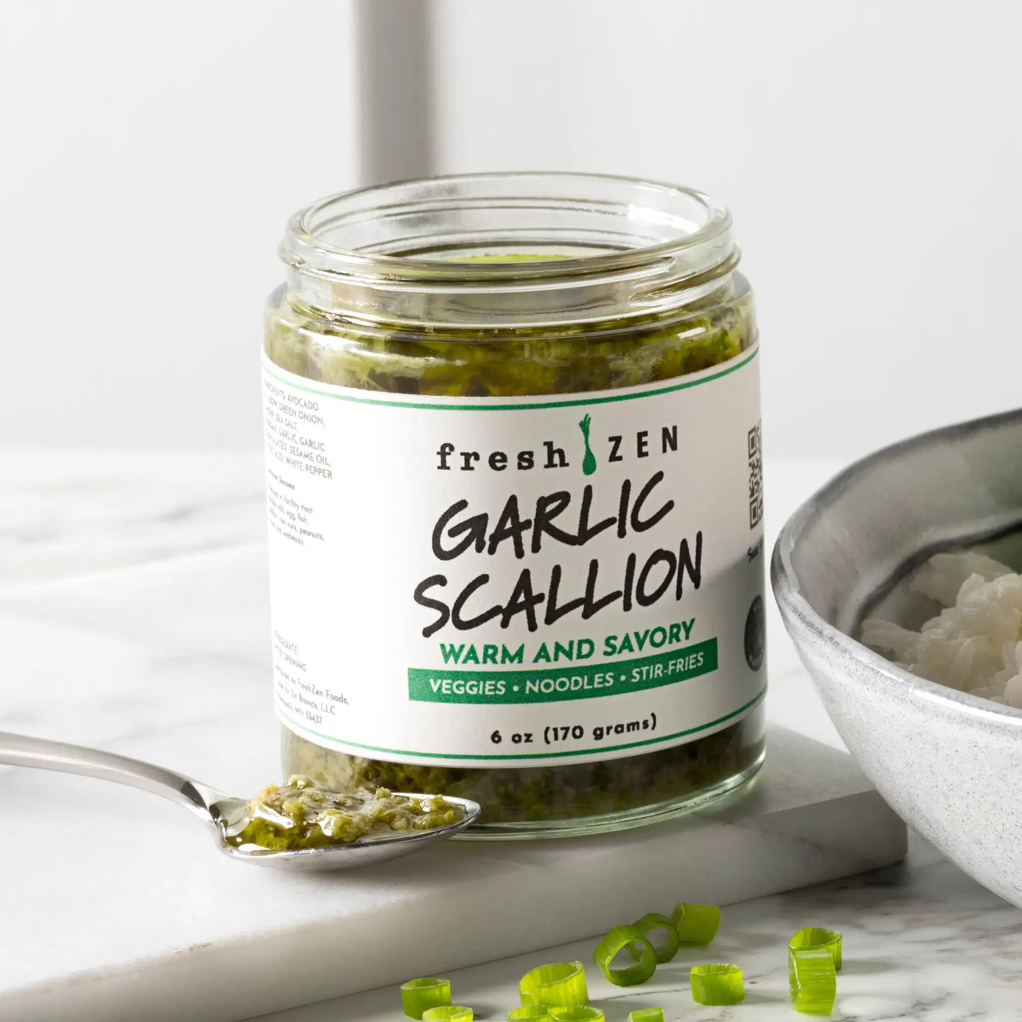 A clear glass jar of fresh zen garlic scallion sauce, labeled with a white and green design.