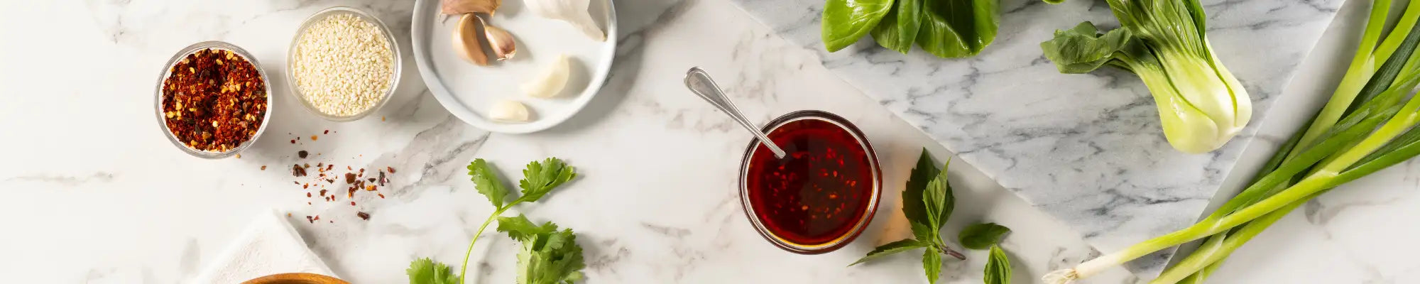 A glass jar filled with a rich, dark red sauce and topped with fresh green basil leaves.