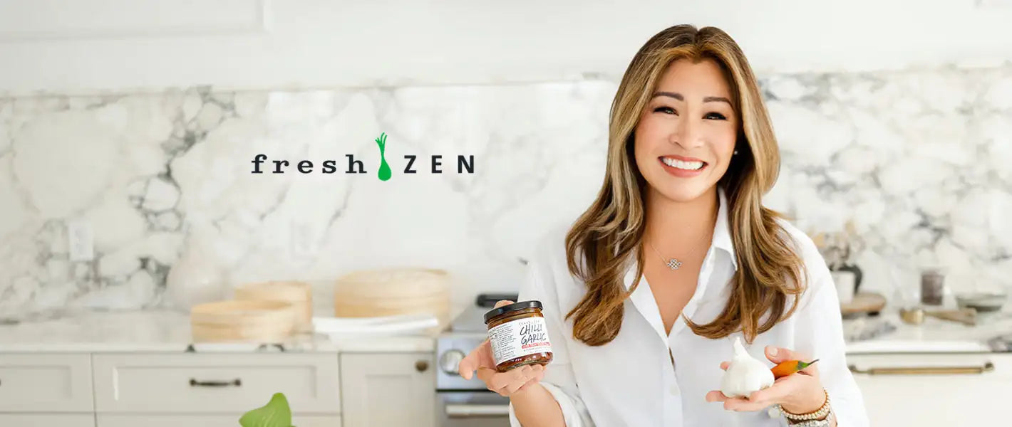 A glass jar of fresh zen brand spread with a brown label and metallic lid, held in the woman’s hand.