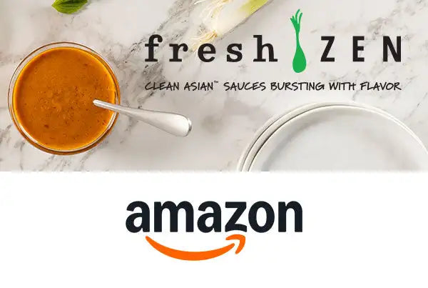 A vibrant orange asian sauce in a clear glass bowl, served with a silver spoon.